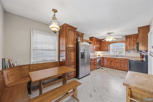 kitchen with sink, tasteful backsplash, decorative light fixtures, appliances with stainless steel finishes, and ceiling fan