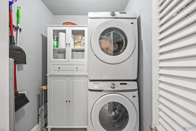 laundry room with stacked washer and clothes dryer and cabinets