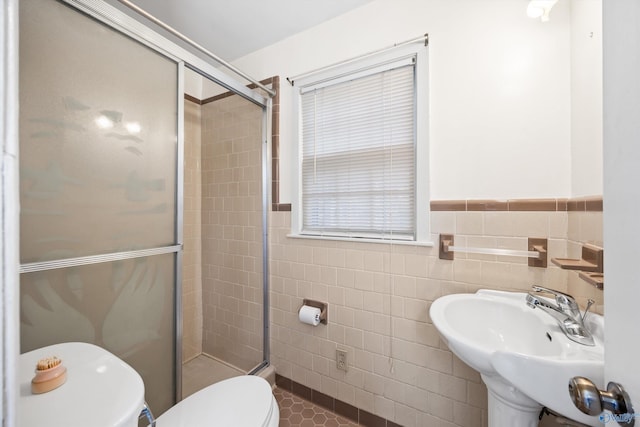 bathroom featuring walk in shower, sink, tile walls, and toilet