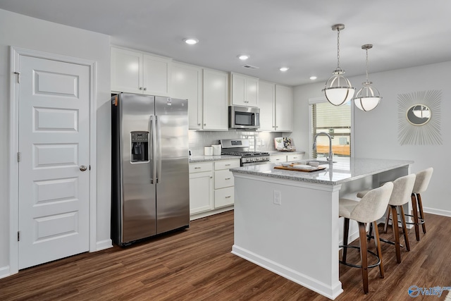 kitchen featuring dark wood-style floors, white cabinetry, a sink, appliances with stainless steel finishes, and backsplash