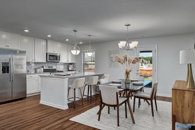 dining space featuring dark wood finished floors, an inviting chandelier, recessed lighting, and a wealth of natural light