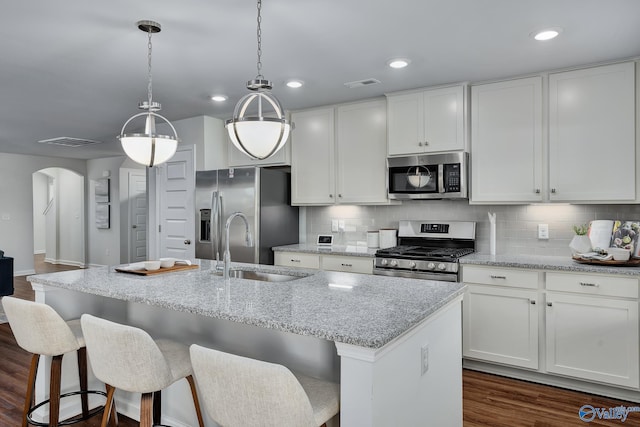kitchen featuring arched walkways, appliances with stainless steel finishes, a sink, and visible vents