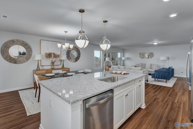kitchen with dark wood-style flooring, light stone countertops, a sink, an island with sink, and stainless steel appliances