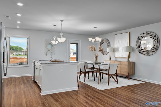 kitchen with dark wood-style flooring, pendant lighting, appliances with stainless steel finishes, a sink, and baseboards