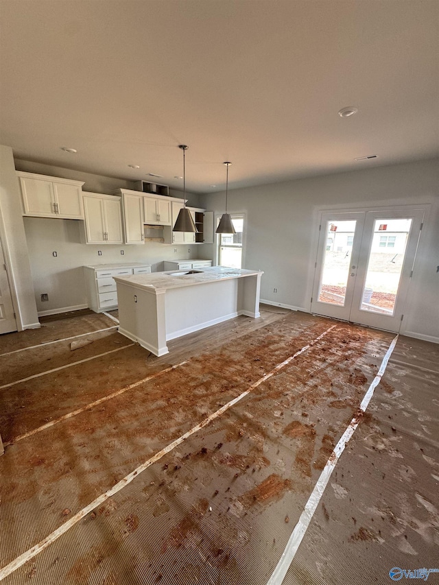 kitchen with white cabinets, pendant lighting, an island with sink, and a healthy amount of sunlight