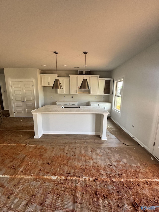 kitchen featuring baseboards, hanging light fixtures, a kitchen island, and white cabinetry