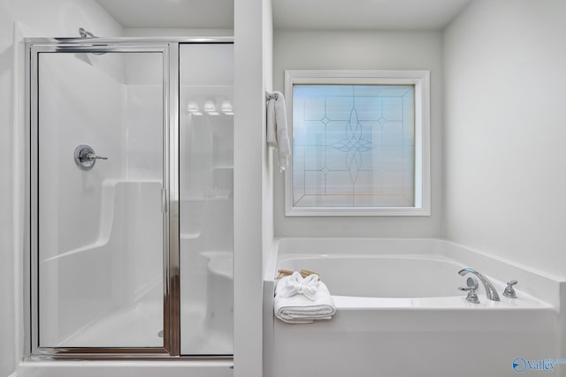 bathroom featuring a garden tub and a shower stall