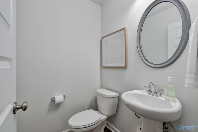 bathroom featuring a sink, baseboards, and toilet