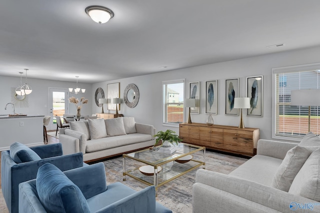 living area with visible vents, wood finished floors, and a chandelier
