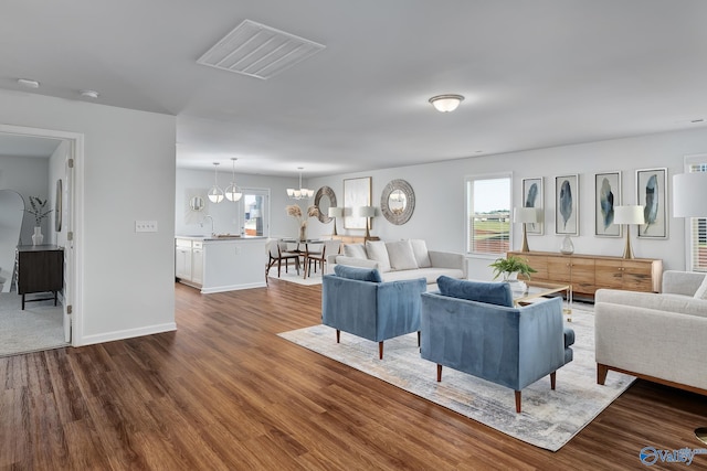 living room featuring plenty of natural light, a notable chandelier, dark wood-style flooring, and visible vents