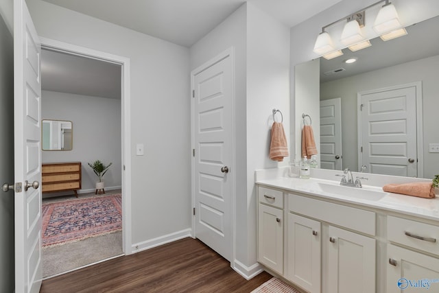 bathroom with baseboards, wood finished floors, and vanity
