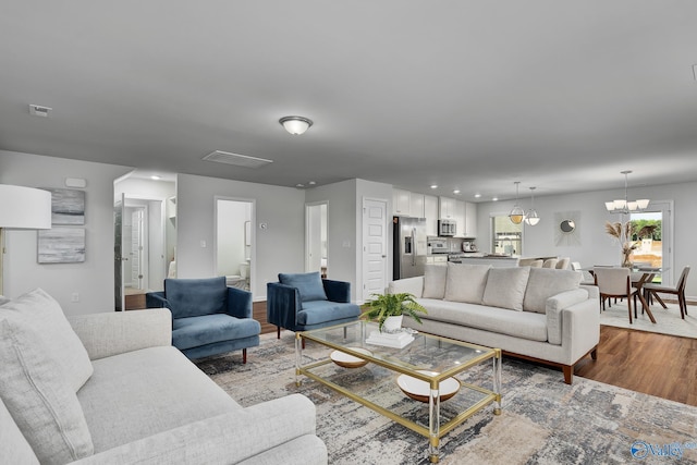 living area with recessed lighting, baseboards, an inviting chandelier, and wood finished floors