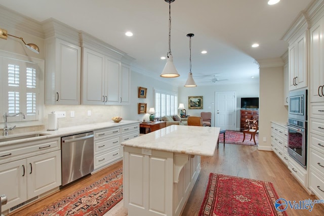 kitchen with appliances with stainless steel finishes, a center island, white cabinetry, sink, and ceiling fan