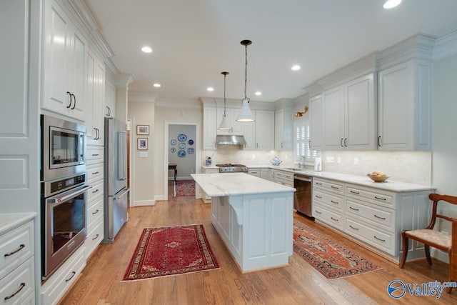 kitchen with white cabinets, appliances with stainless steel finishes, pendant lighting, and a kitchen island