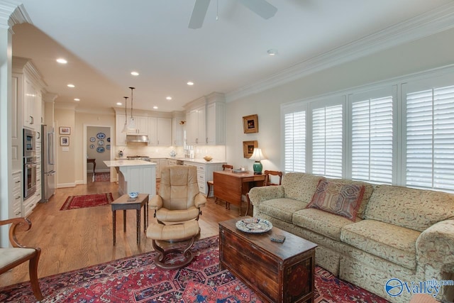 living room featuring ceiling fan, light hardwood / wood-style flooring, and crown molding