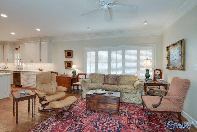 living room featuring ceiling fan, light hardwood / wood-style floors, and crown molding