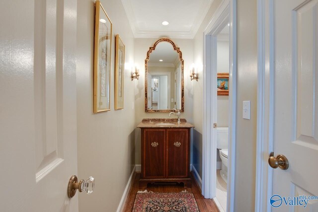 bathroom featuring toilet, vanity, wood-type flooring, and ornamental molding