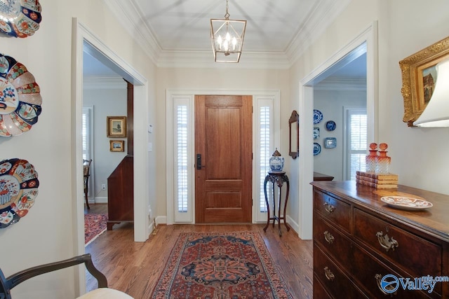 foyer with crown molding, hardwood / wood-style floors, and a notable chandelier