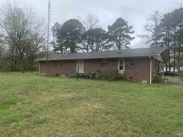 rear view of property with crawl space, brick siding, and a yard