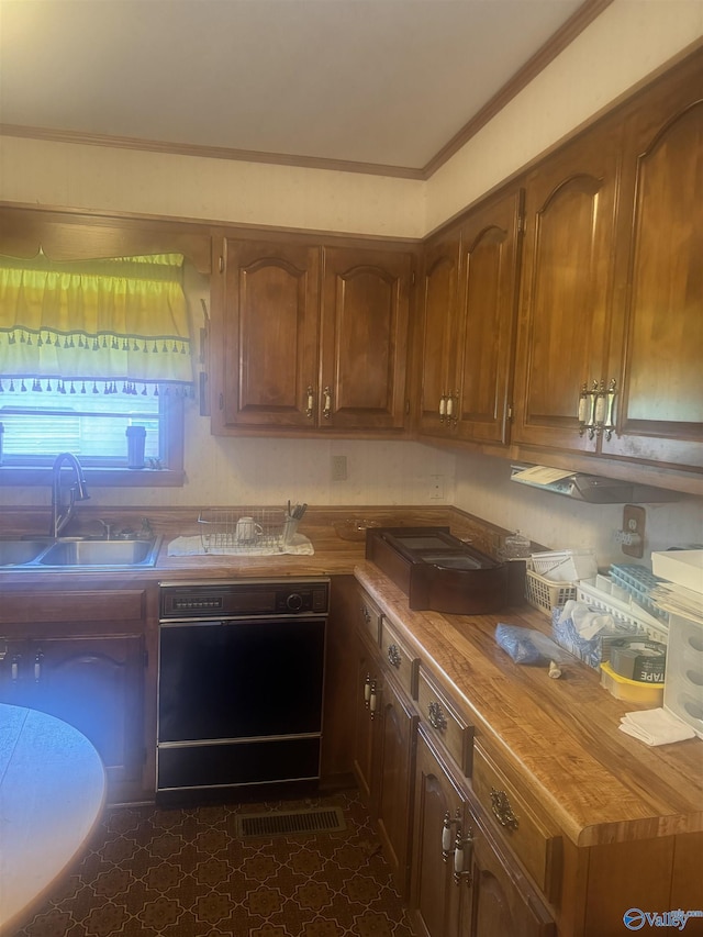kitchen featuring black dishwasher, brown cabinetry, crown molding, and a sink