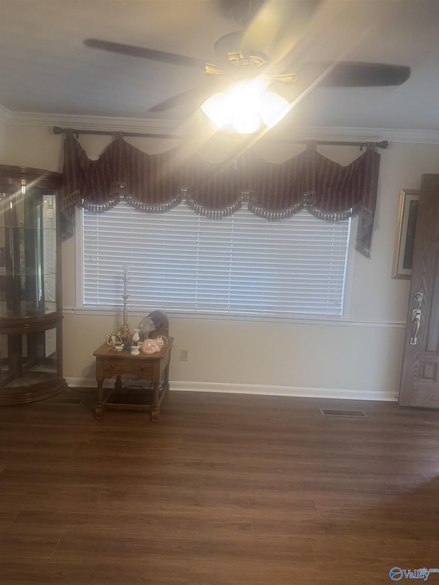 spare room with wood finished floors, ceiling fan, baseboards, ornamental molding, and visible vents