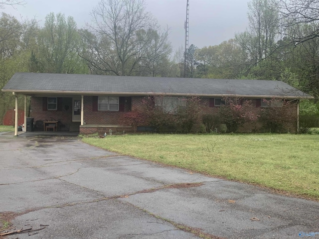 ranch-style house featuring brick siding, a carport, a front lawn, and aphalt driveway