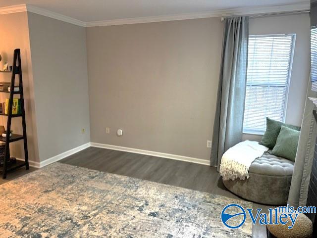 sitting room with crown molding and dark wood-type flooring