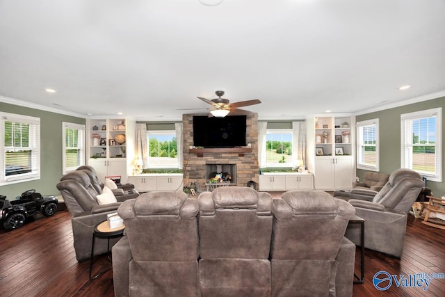 living room featuring dark wood-style flooring, a fireplace, ceiling fan, built in features, and crown molding