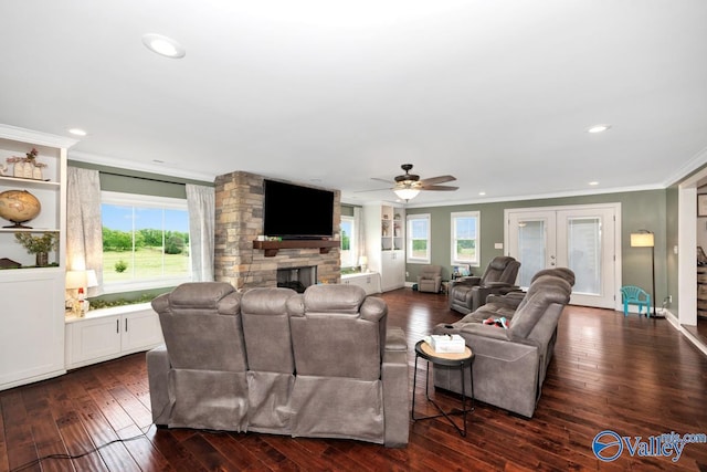 living area featuring crown molding, recessed lighting, dark wood finished floors, a ceiling fan, and a stone fireplace