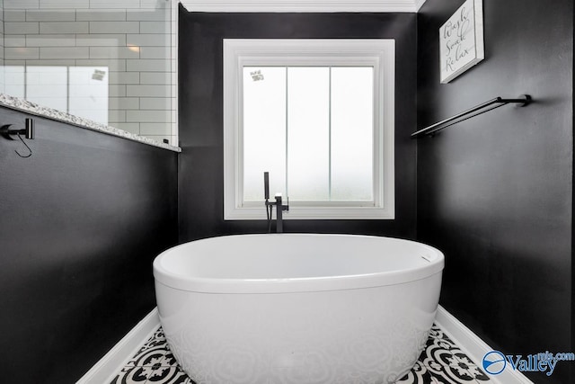 full bath with a freestanding tub, a wealth of natural light, and baseboards