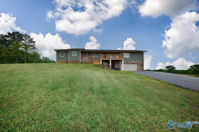 ranch-style house with a deck, driveway, stone siding, a front yard, and an attached garage
