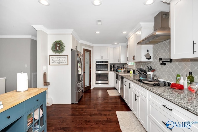 kitchen featuring appliances with stainless steel finishes, dark wood-type flooring, white cabinetry, and wall chimney exhaust hood