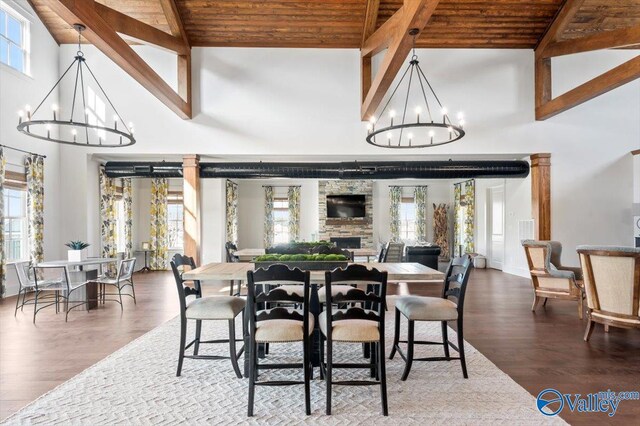 living room featuring hardwood / wood-style flooring, ornamental molding, a fireplace, ornate columns, and a notable chandelier