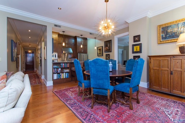 dining room featuring light wood-type flooring, crown molding, and an inviting chandelier