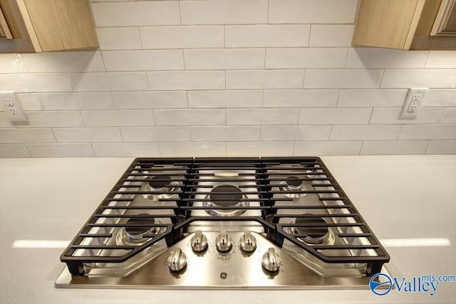 details featuring stainless steel gas cooktop and decorative backsplash