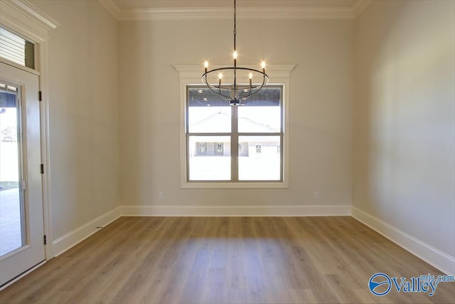 unfurnished dining area featuring crown molding, a notable chandelier, and light wood-type flooring