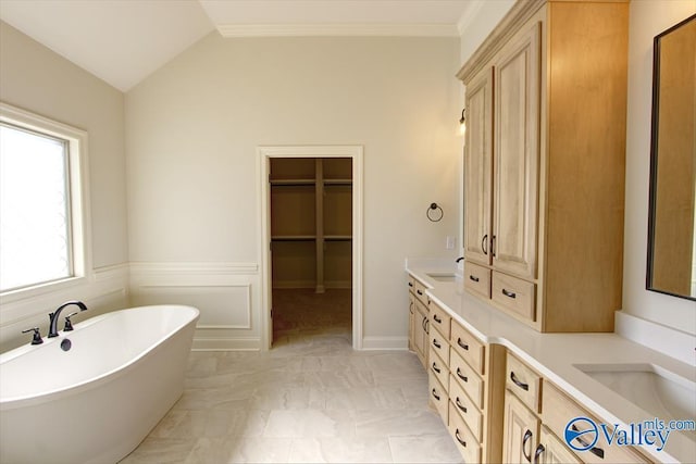 bathroom with crown molding, vanity, vaulted ceiling, and a tub