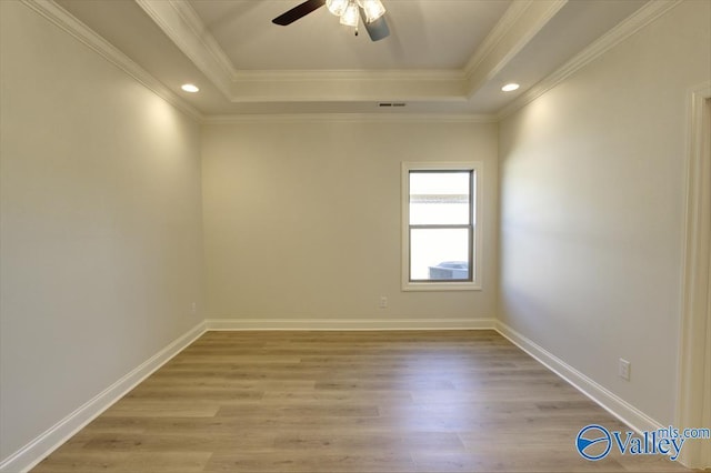 unfurnished room with crown molding, a raised ceiling, and light hardwood / wood-style floors