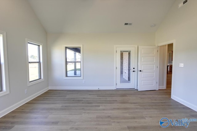 unfurnished room featuring high vaulted ceiling and light hardwood / wood-style flooring