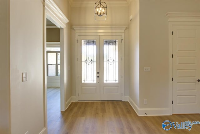 entrance foyer featuring french doors, ornamental molding, a healthy amount of sunlight, and light hardwood / wood-style floors