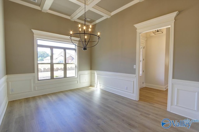 unfurnished dining area with hardwood / wood-style flooring, coffered ceiling, a chandelier, and beam ceiling