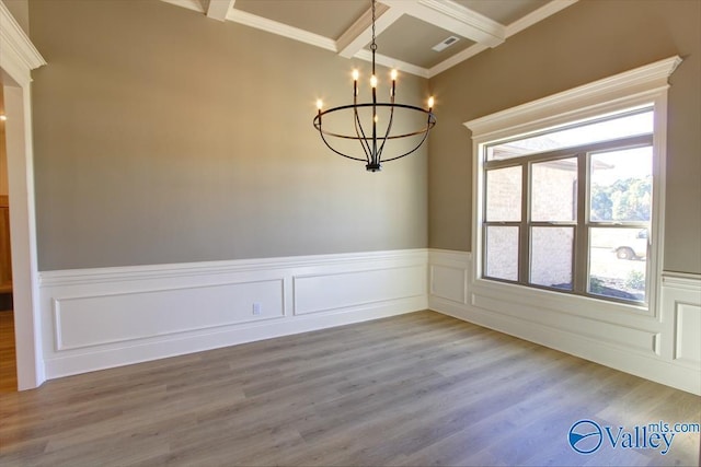 unfurnished dining area with an inviting chandelier, hardwood / wood-style floors, beam ceiling, coffered ceiling, and ornamental molding