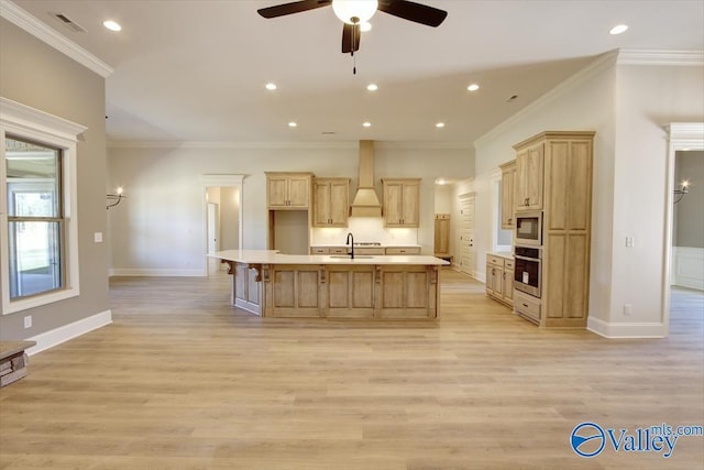 kitchen with premium range hood, a kitchen island with sink, light hardwood / wood-style floors, built in microwave, and stainless steel oven