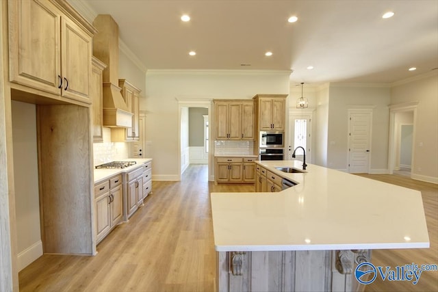 kitchen with light brown cabinetry, sink, a spacious island, and appliances with stainless steel finishes