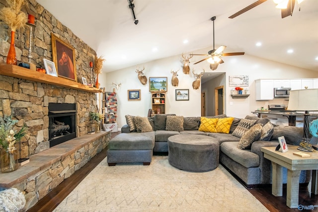 living room featuring a stone fireplace, ceiling fan, lofted ceiling, and hardwood / wood-style flooring