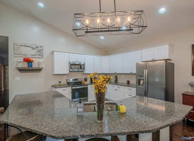 kitchen featuring white cabinets, dark stone countertops, lofted ceiling, and stainless steel appliances