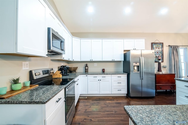 kitchen featuring dark stone countertops, white cabinetry, dark wood-type flooring, and stainless steel appliances