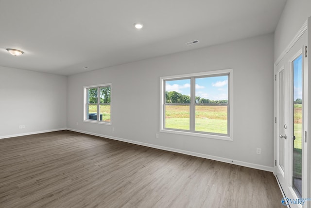 empty room with dark wood-style flooring, baseboards, visible vents, and recessed lighting