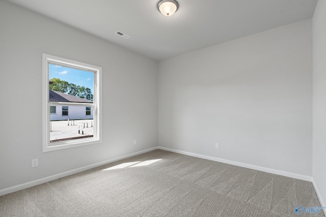 carpeted spare room with visible vents and baseboards