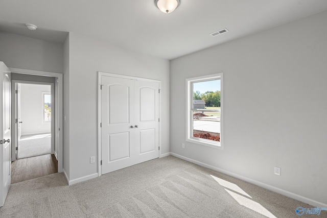 unfurnished bedroom with visible vents, multiple windows, and carpet flooring